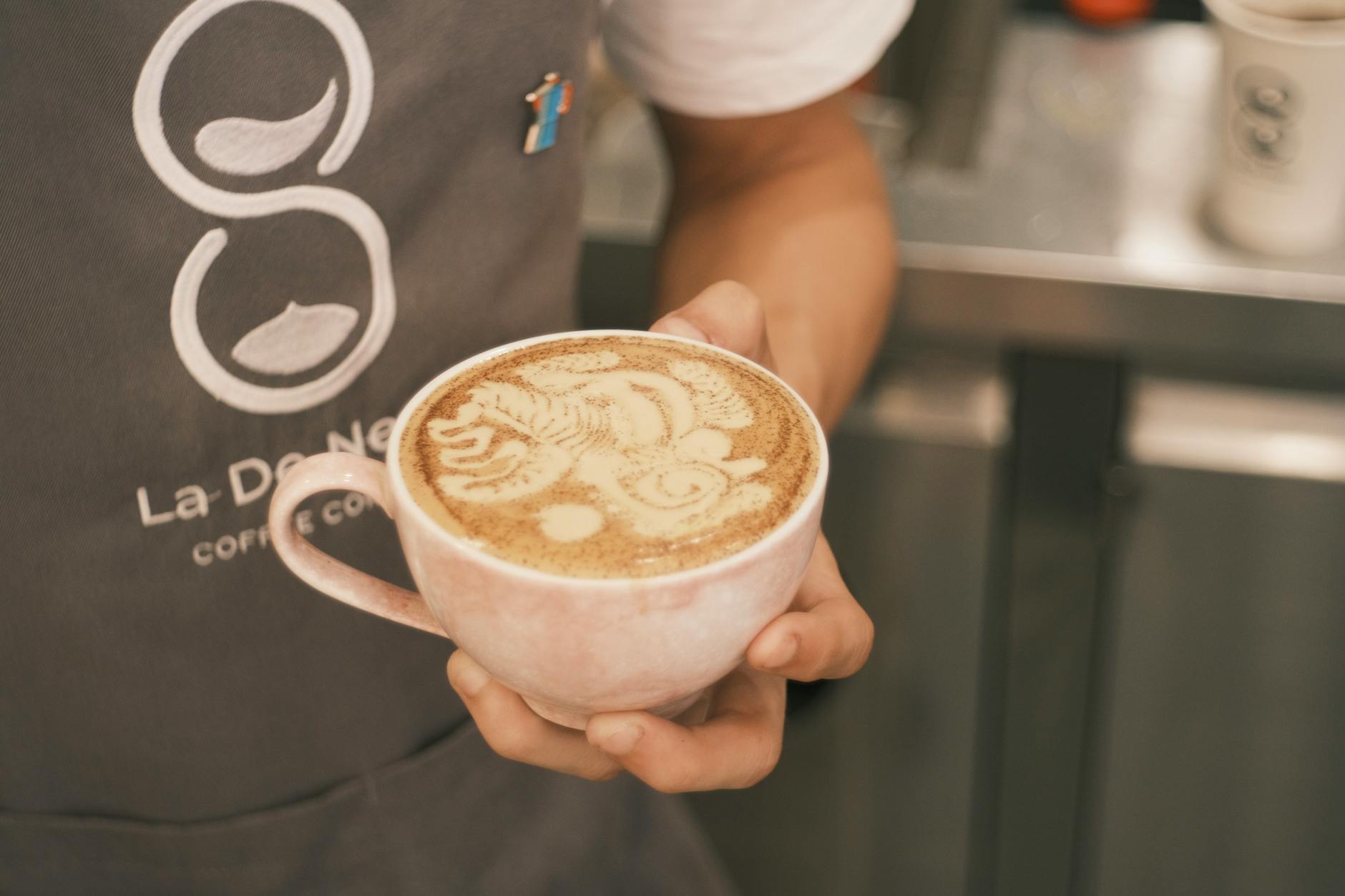 Barista pouring latte art in a speciality coffee shop in Manchester