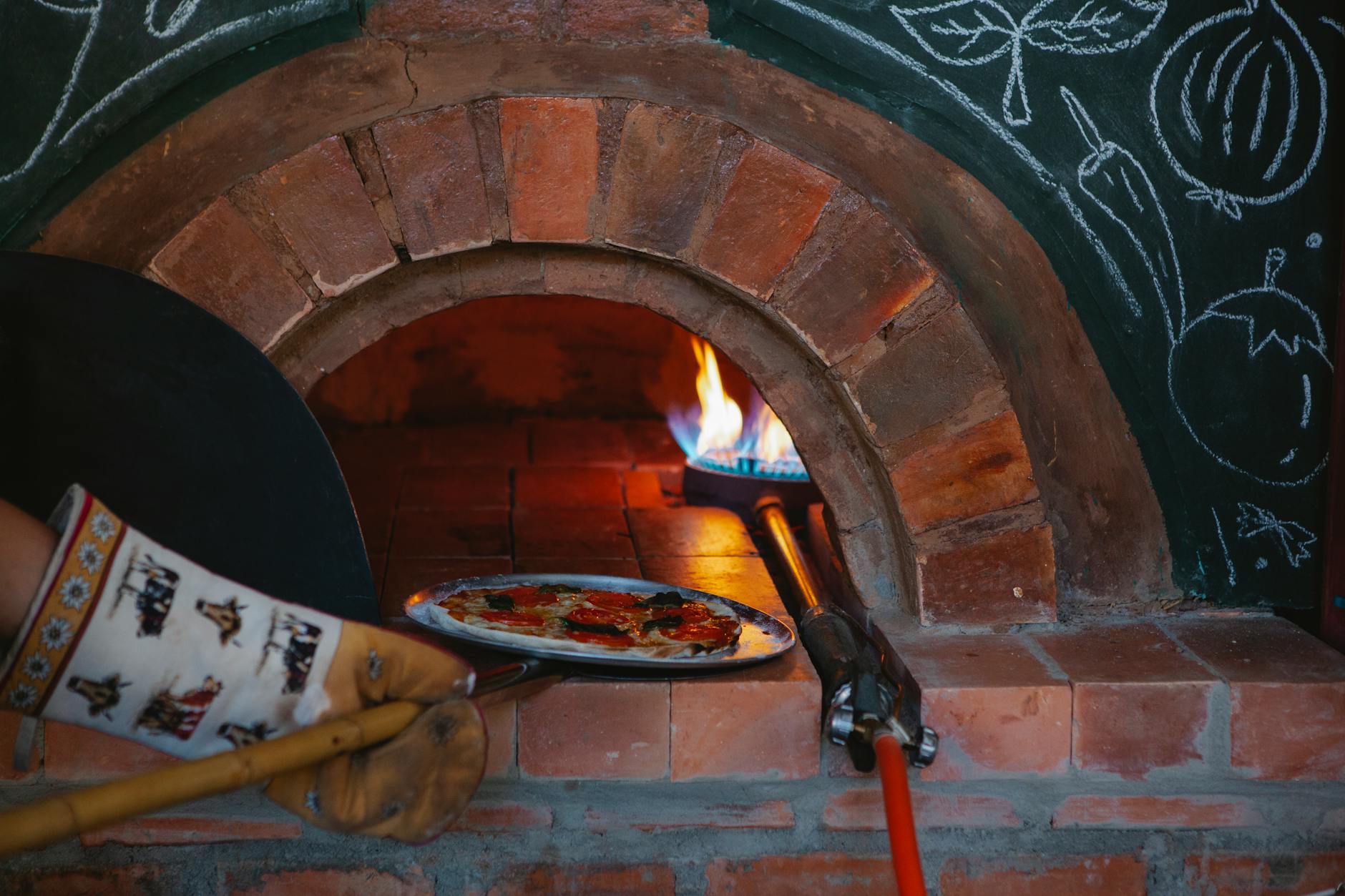 Wood-fired pizza being prepared in a traditional oven at a Manchester pizzeria