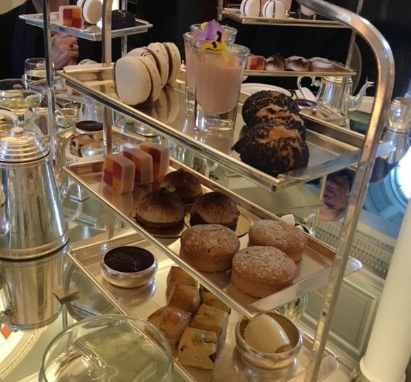 Best Afternoon Tea in Manchester: 20 Places Worth Booking 5 A three-tier silver afternoon tea stand holding scones, finger sandwiches, macarons and small pastries, with a teapot alongside