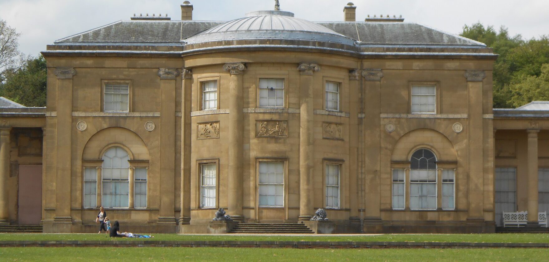 The domed neoclassical south front of Heaton Hall across a sunny lawn in Heaton Park