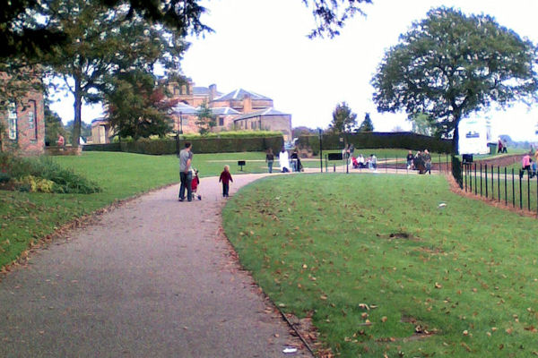 Heaton Park: Complete Visitor Guide 2 A curving path across the lawns of Heaton Park with families walking and the hall buildings beyond