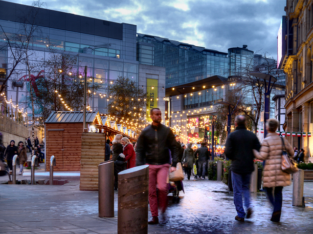 Manchester Christmas Markets Food & Drink: What to Eat & Drink 7 Shoppers walking through the Exchange Square Christmas market under strings of lights