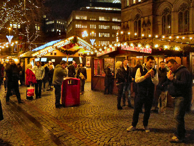 Crowds eating at the Albert Square Christmas market beside Dutch mini pancake and Flammkuchen stalls