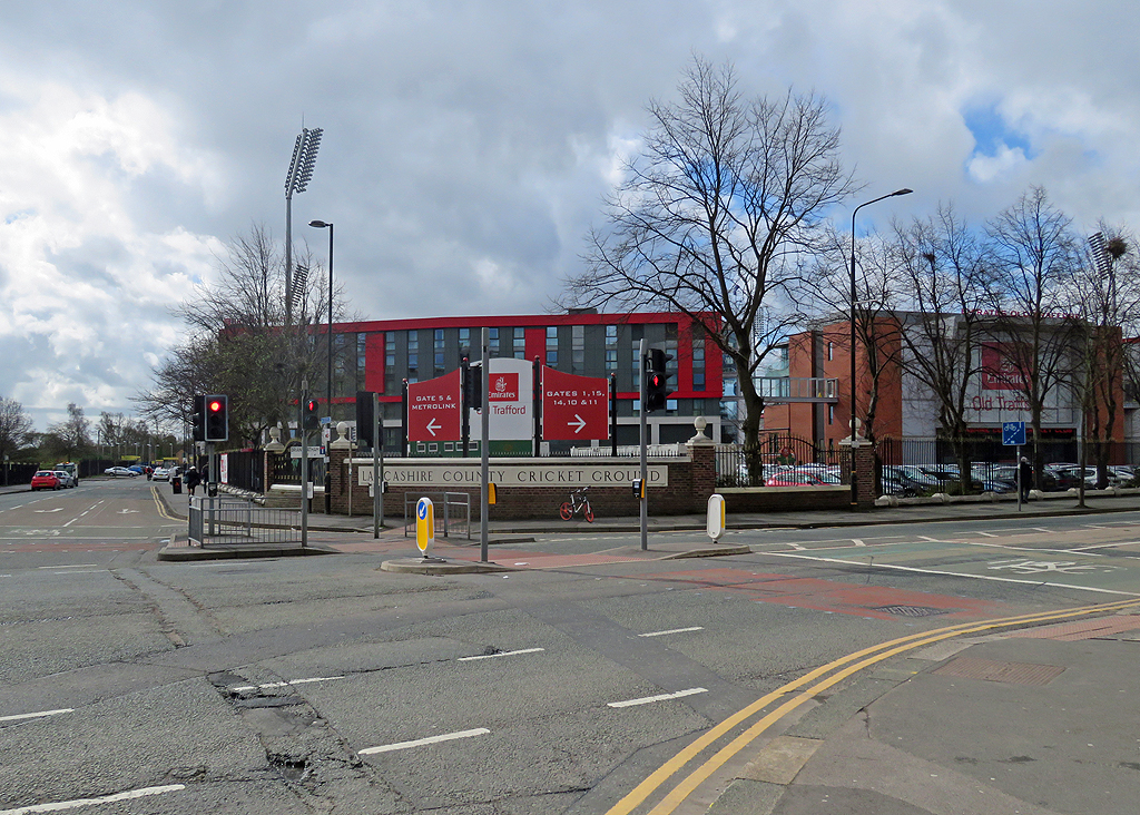 Emirates Old Trafford: Cricket, Concerts & Match Days 6 A road junction leading to Old Trafford Cricket Ground, with floodlights and red-clad modern buildings beyond