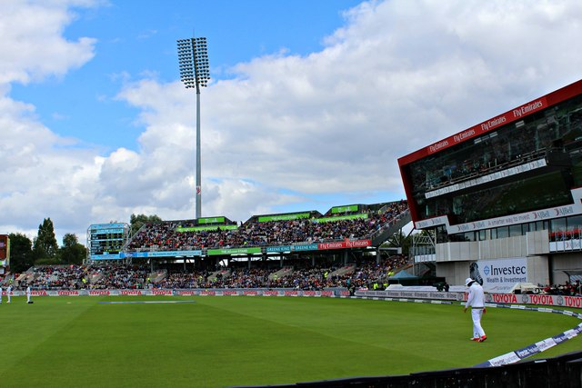 Emirates Old Trafford: Cricket, Concerts & Match Days 4 A packed stand of spectators at Emirates Old Trafford under a floodlight pylon, with a fielder on the boundary