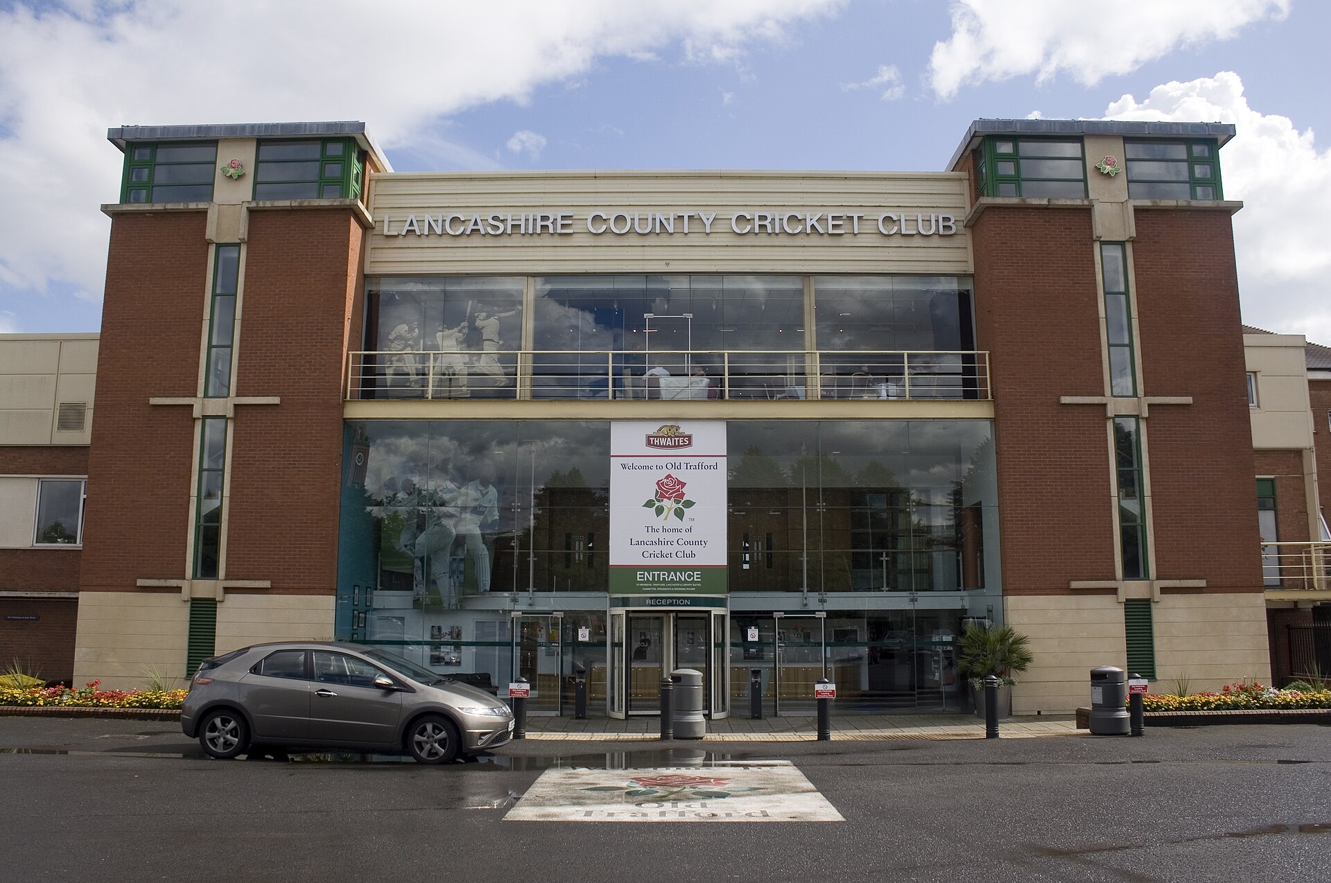 Emirates Old Trafford: Cricket, Concerts & Match Days 2 The brick and glass main entrance of Lancashire County Cricket Club with the club crest above the doors