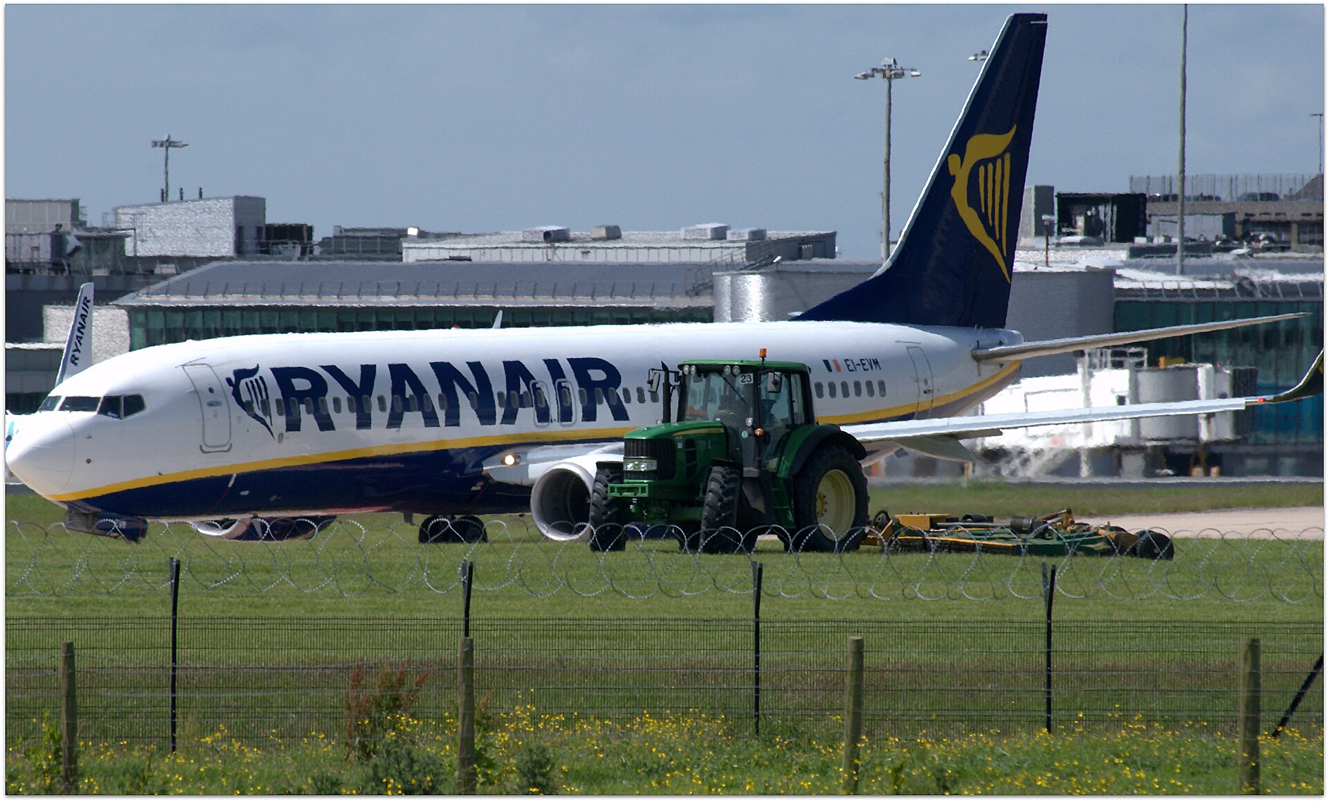 Manchester Airport Arrivals: What to Do the Moment You Land 2 A Ryanair Boeing 737-800 on the airfield at Manchester Airport with a tractor mowing the grass beside it