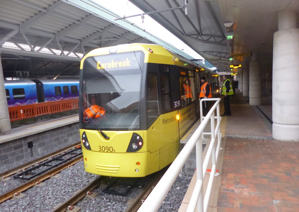 Manchester Airport Arrivals: What to Do the Moment You Land 6 A yellow Metrolink tram at the Manchester Airport tram stop under the station canopy