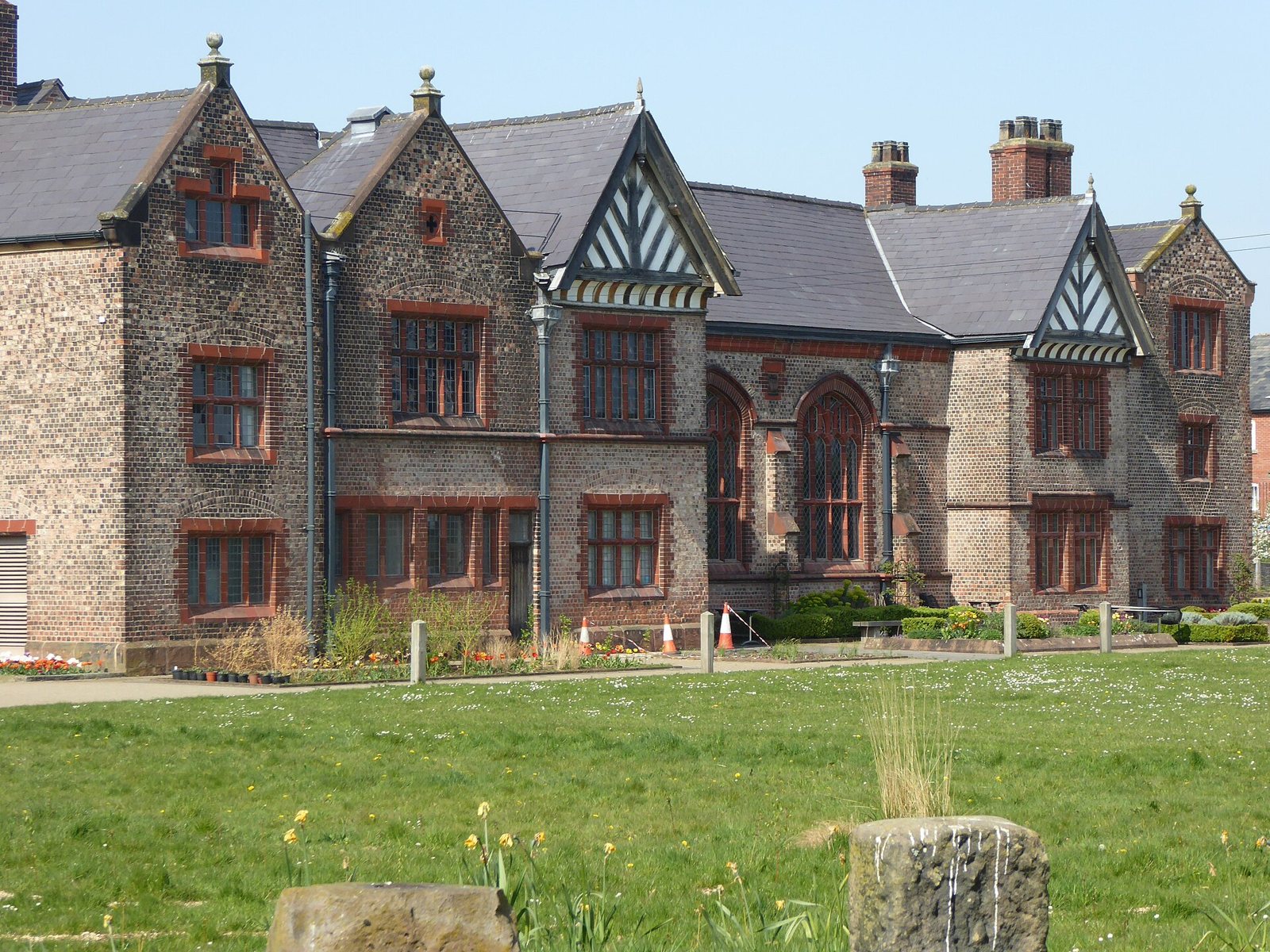 The black-and-white timbered gables and brick wings of Ordsall Hall in Salford, seen across a lawn